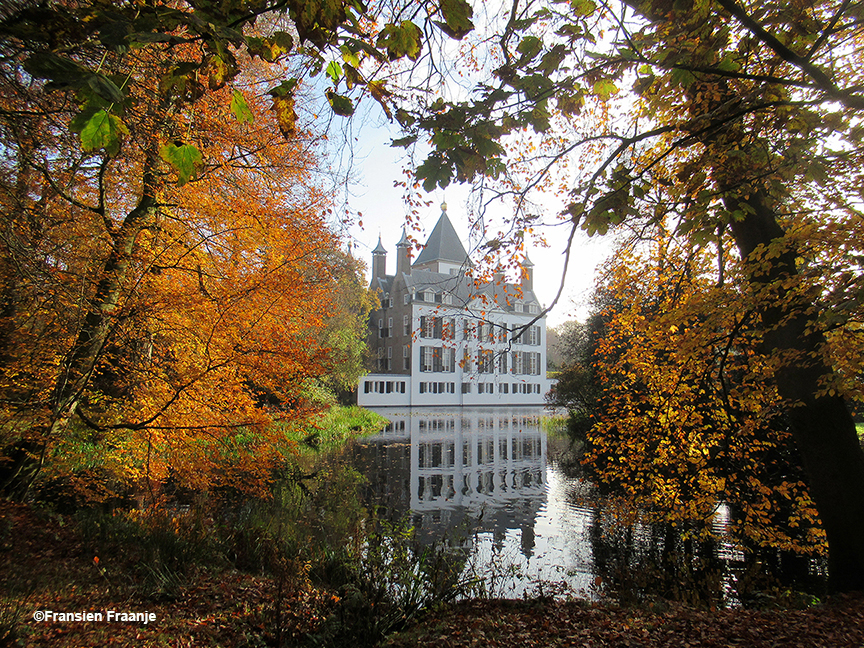 Het kasteel weerspiegelt in de vijver, waarbij de bomen een soort van ereboog vormen - Foto: ©Fransien Fraanje