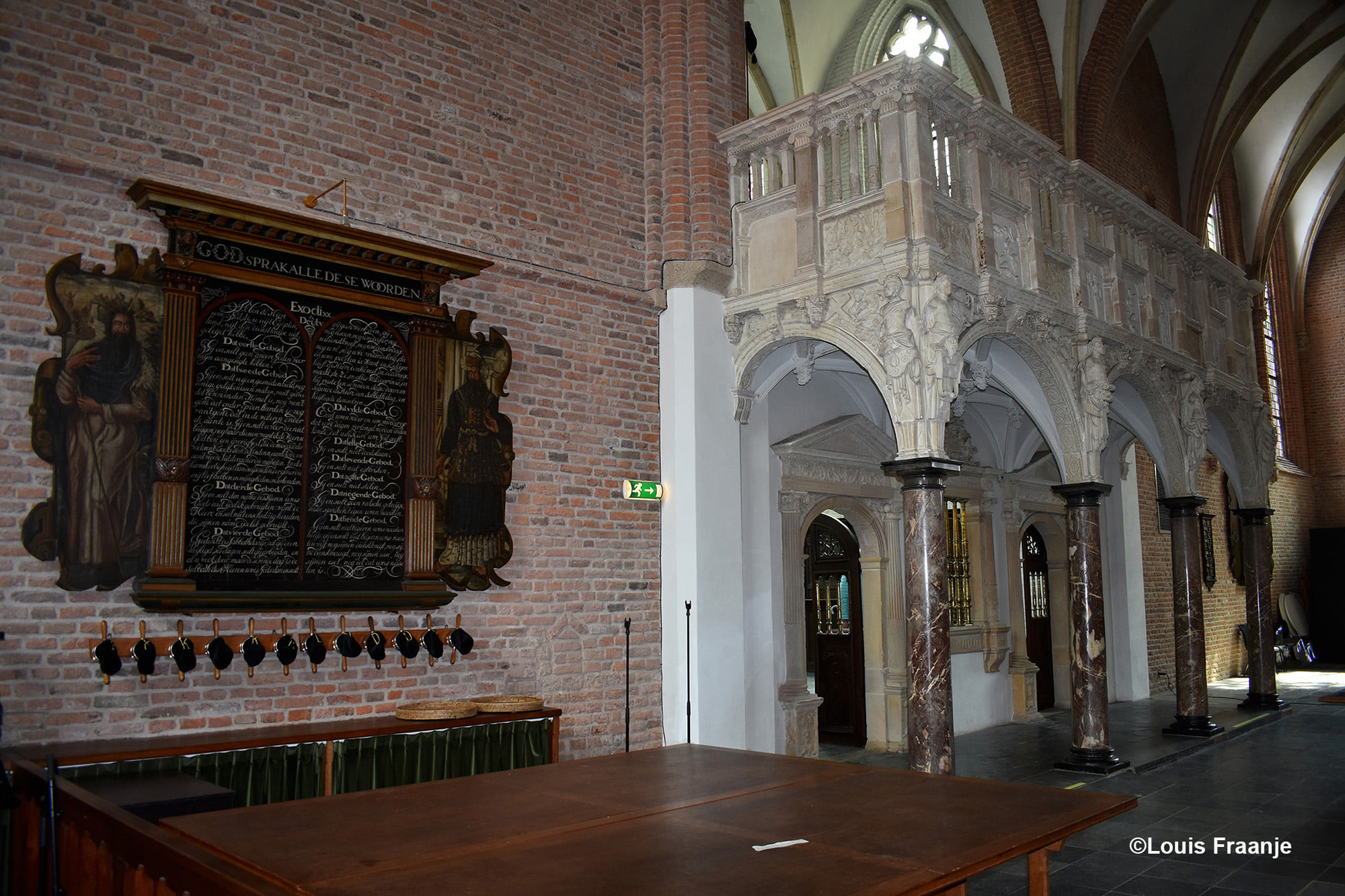 Met links naast het oksaal een prachtig wandbord met de tien geboden, met eronder de kerkzakken voor de collecte - Foto: ©Louis Fraanje