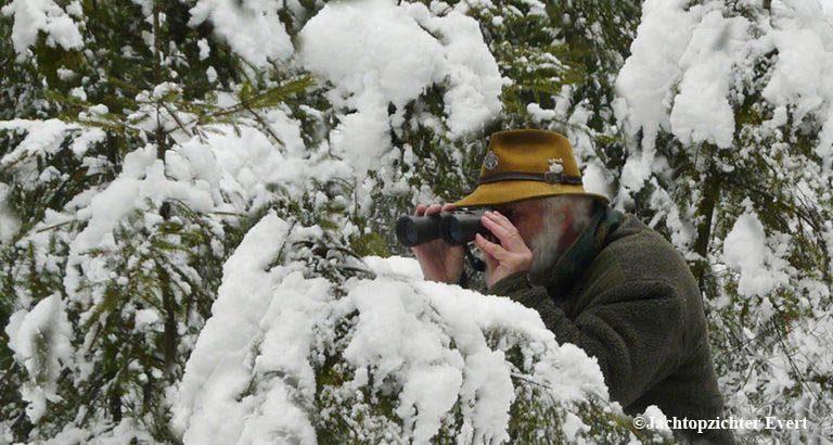 Vanachter een besneeuwde den, speur ik met de kijker naar wild – Foto: ©Jachtopzichter Evert